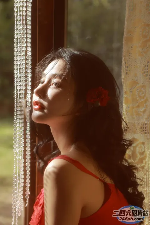身穿红色连衣裙的阿拉伯女郎，戴着串珠窗帘望向窗外