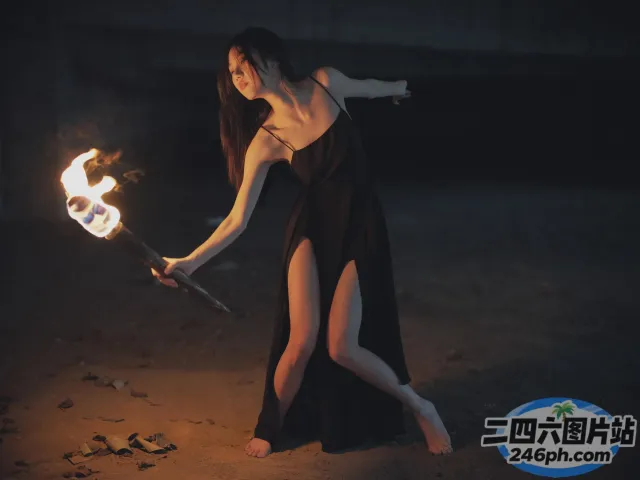 身穿黑色连衣裙的 arafed 女子手持火棍
