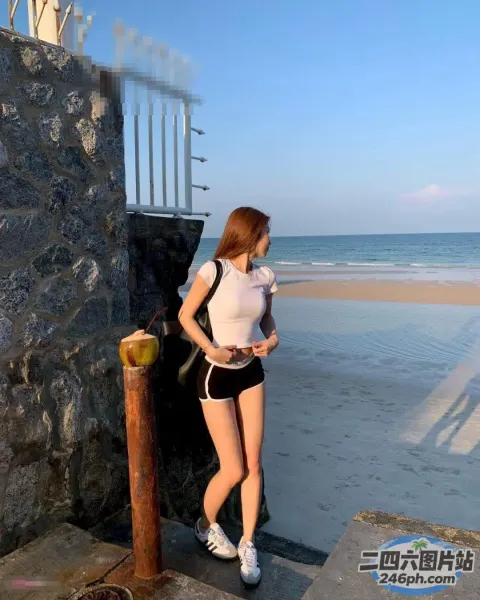 海滩上站着一个女人，手里拿着手机