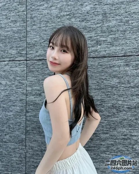 一个穿着白色连衣裙的女人站在墙前的特写