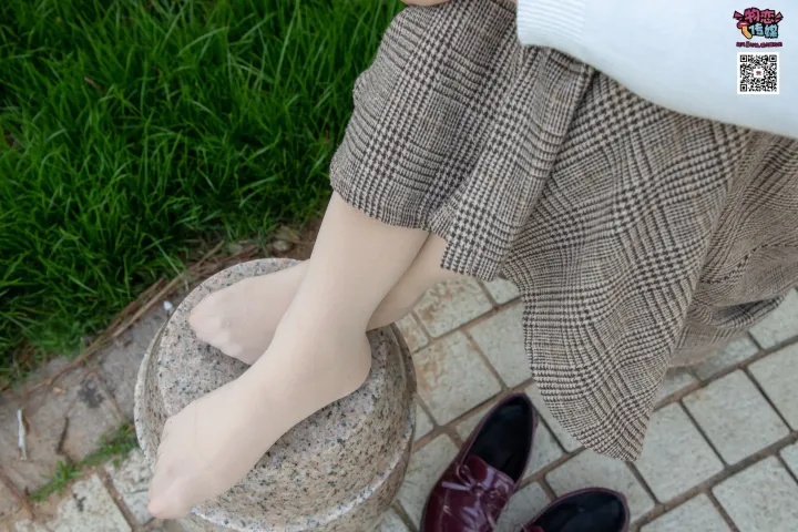 有一个女人站在石基座上，双脚放在凳子上