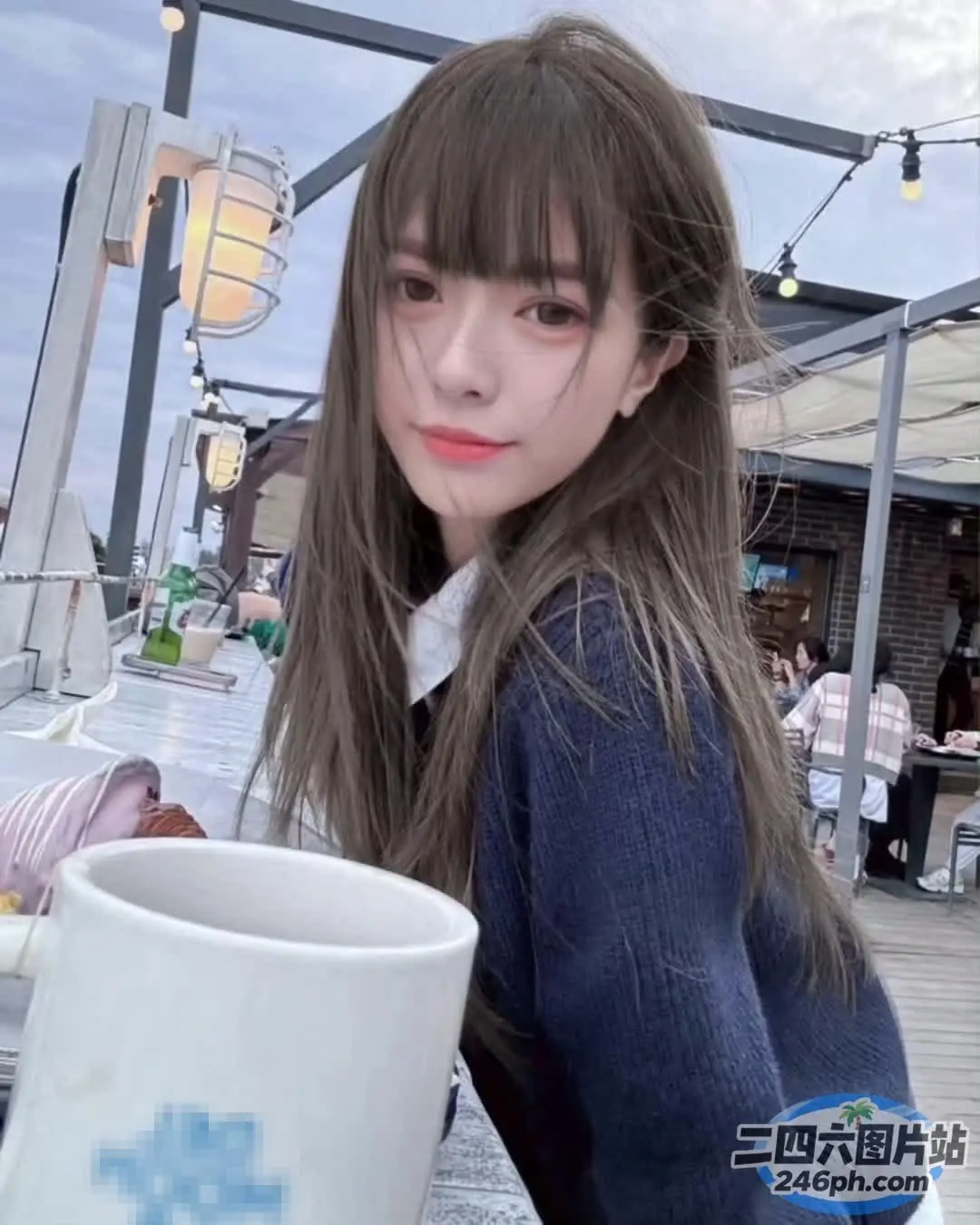 有个女人坐在桌子旁，手里拿着一杯咖啡