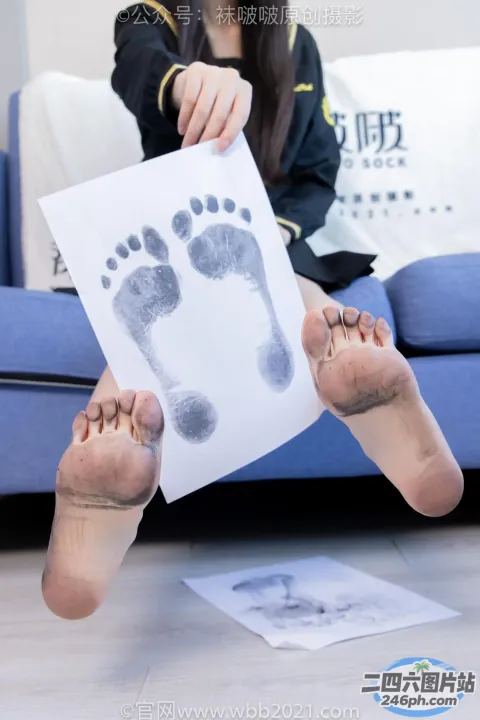 坐在沙发上的阿拉夫德女人拿着一张纸，上面印着婴儿的脚印