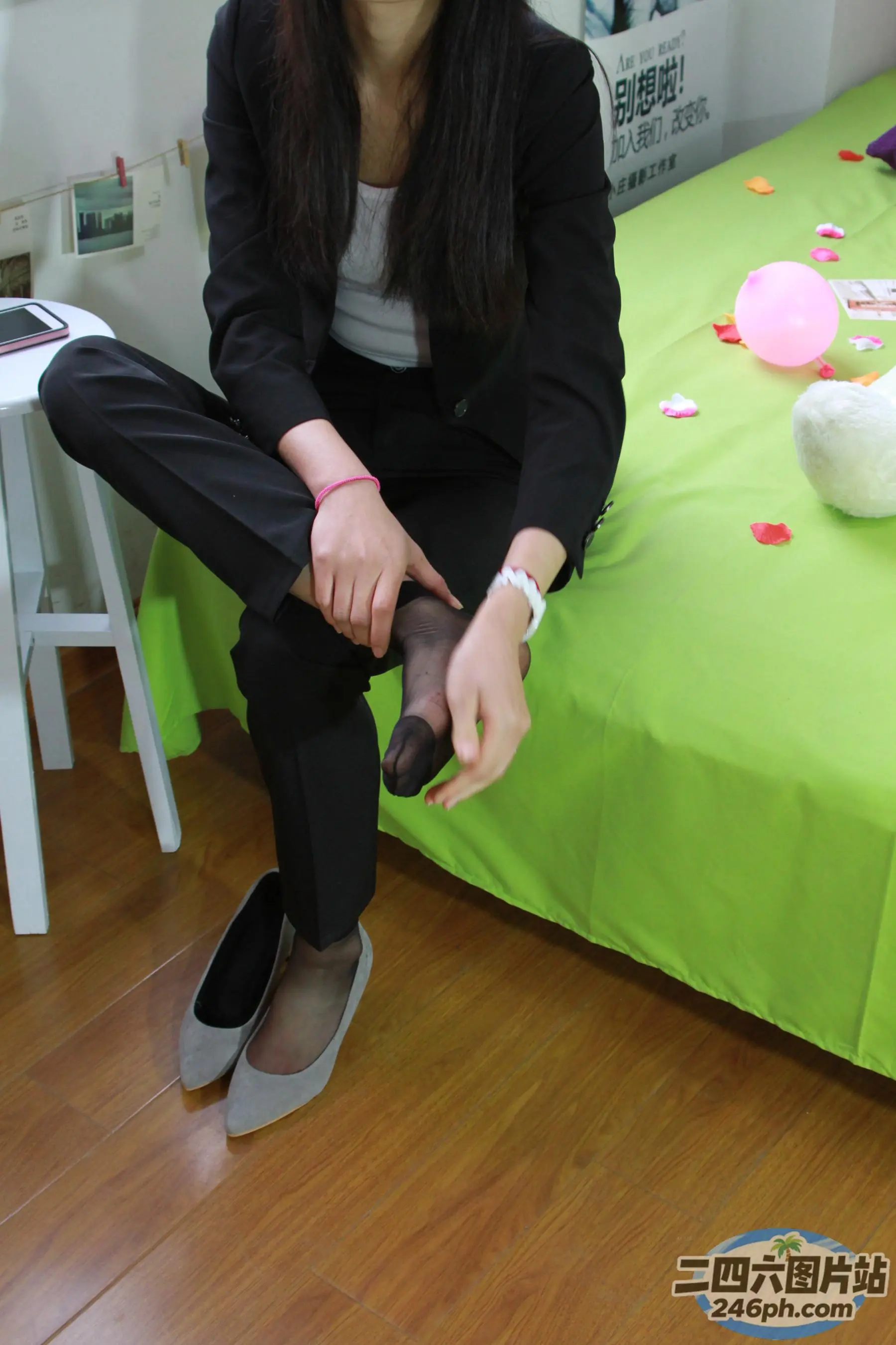 女人坐在一张床上，床上铺着绿色的床单和绿色的桌布