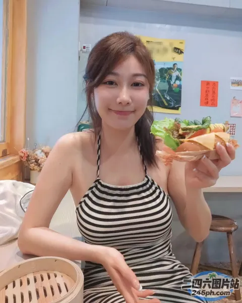 身穿条纹连衣裙的 araffe 女子手里拿着一个三明治