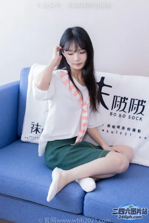 一个女人坐在蓝色的沙发上，手里拿着一个枕头和一个枕头
