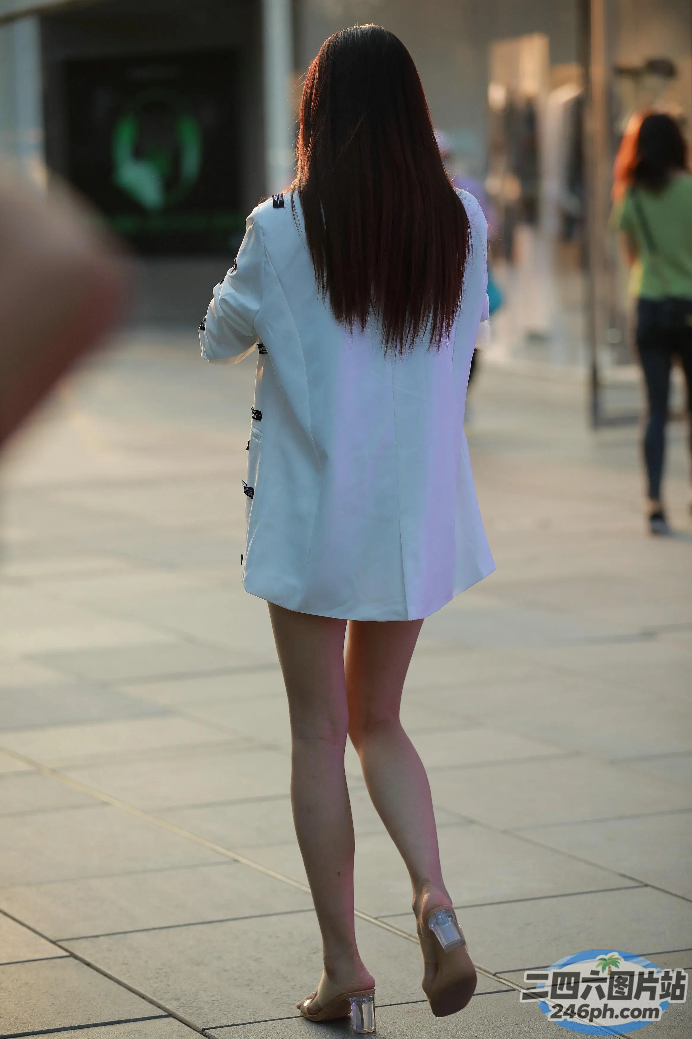 阿拉菲女子穿着白色西装外套走在人行道上