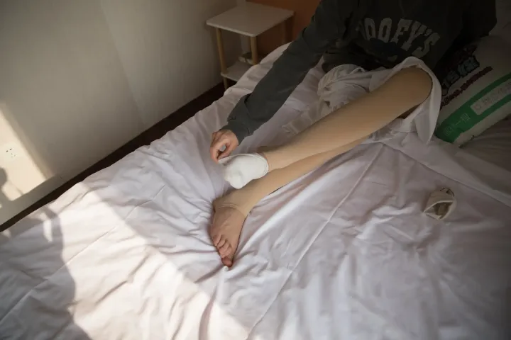 有人躺在一张床上，上面有白色的床单和白色的枕头