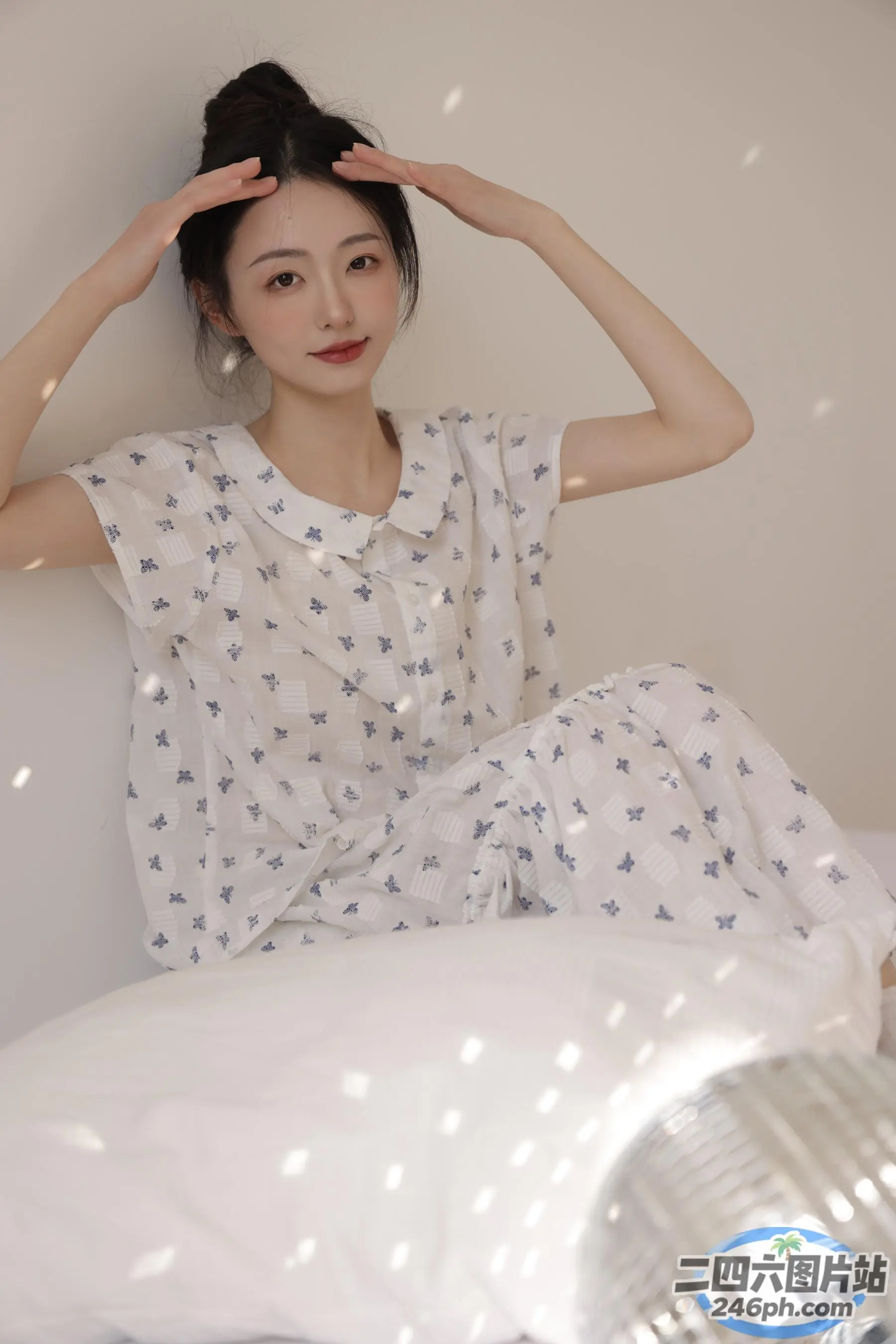 一个女人坐在一张床上，上面有一个白色的枕头和一个白色的枕头
