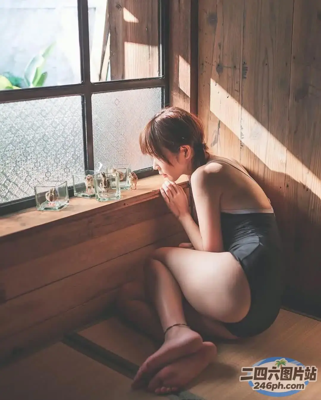 有一个女人坐在地板上，望着窗外