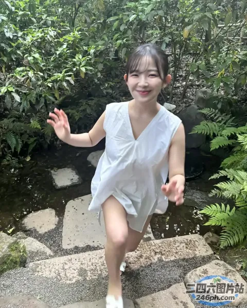 身穿白色连衣裙的 arafed 亚洲女孩沿着石板路奔跑
