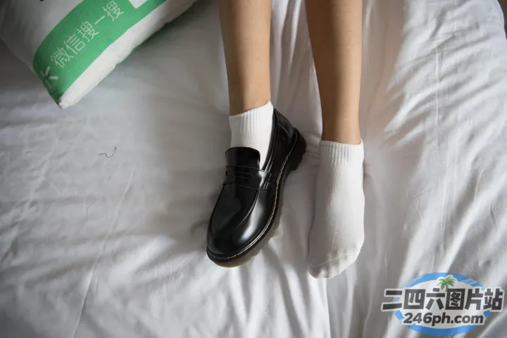有人穿着黑色鞋子和白色袜子躺在床上