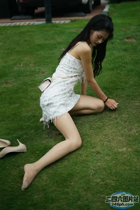 穿着白色连衣裙坐在草地上的 Araffe 女子