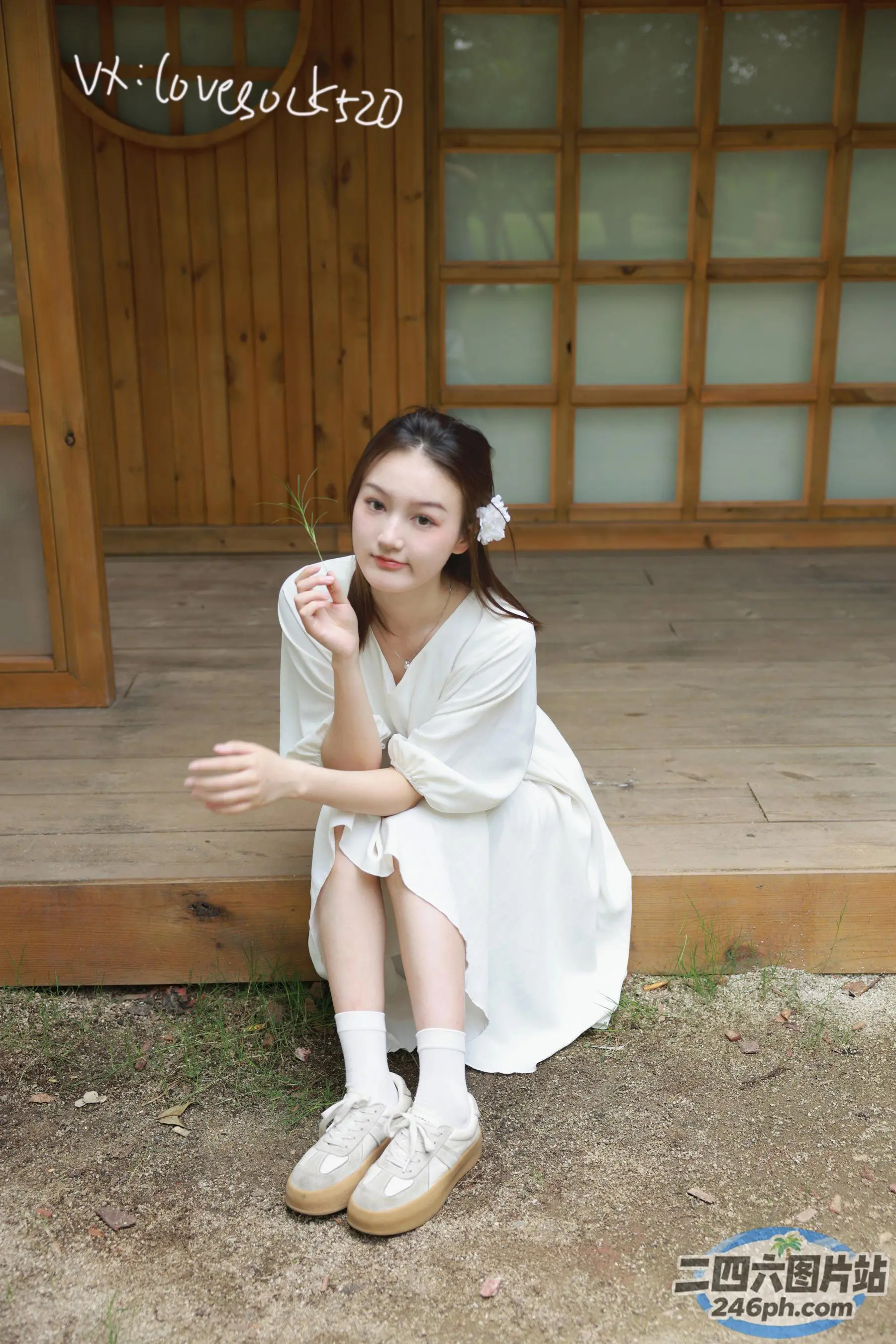 一个女人坐在木制门廊上，头发上插着一朵花