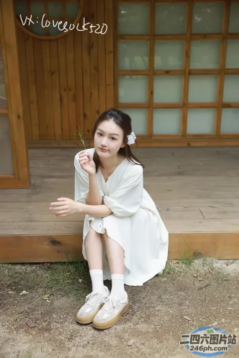 一个女人坐在木制门廊上，头发上插着一朵花
