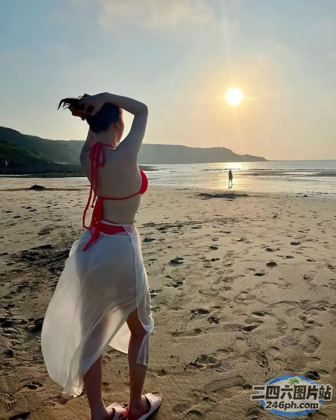 有一个女人站在沙滩上，手里拿着冲浪板