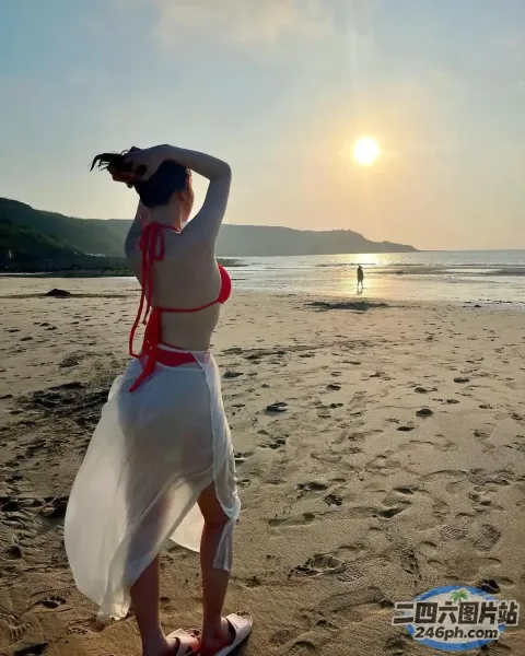 有一个女人站在沙滩上，手里拿着冲浪板