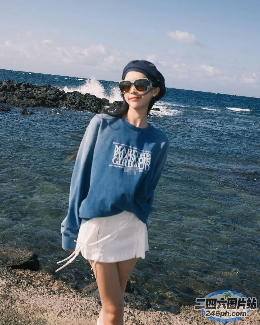 穿着蓝色运动衫的阿拉夫德女人站在海边的海滩上