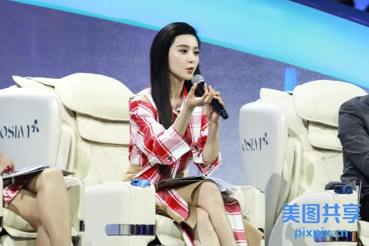 身穿红白相间连衣裙的女士坐在拿着麦克风的白色椅子上