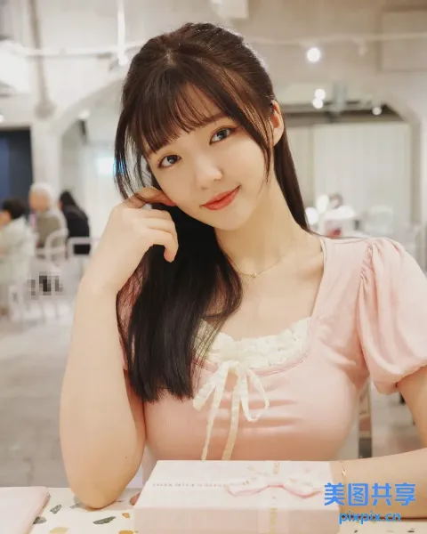阿拉菲女人坐在桌子旁，手里拿着一盒饼干
