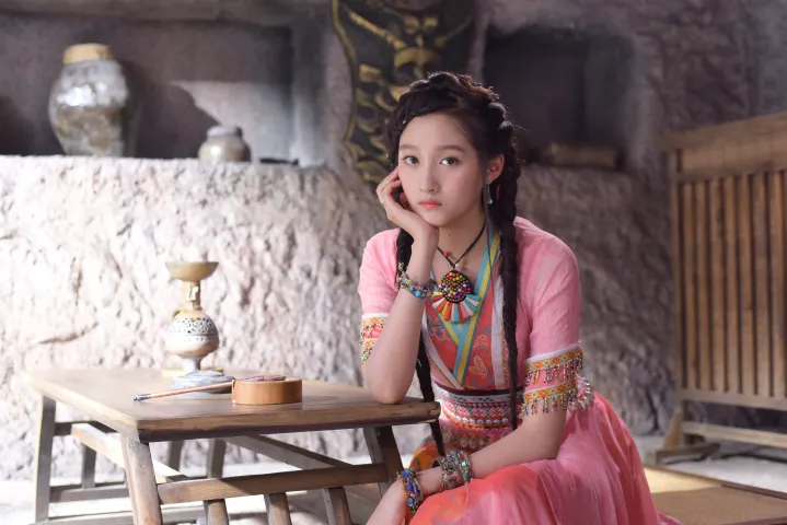 有一个女人坐在一张桌子旁，端着一杯咖啡