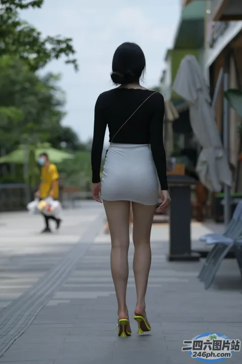 Araffe 穿着短裙，手里拿着钱包走在人行道上