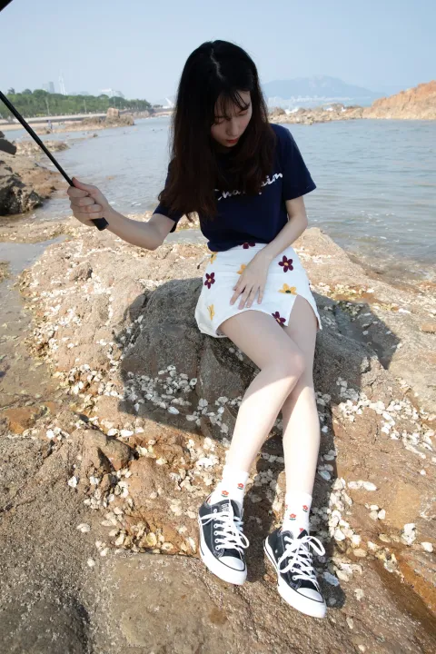 有个女人坐在岩石上，手里撑着伞