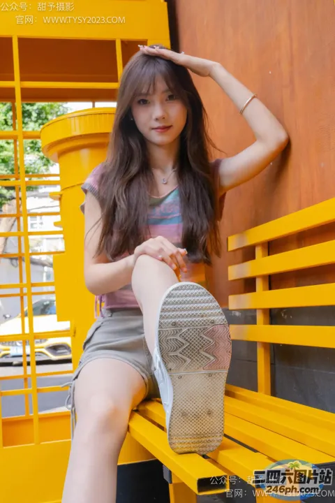 阿拉菲坐在长凳上，脚踩在黄色长凳的靠背上