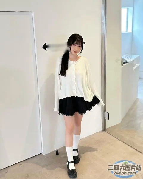 房间里站着一个女人，穿着白衬衫和黑裙子