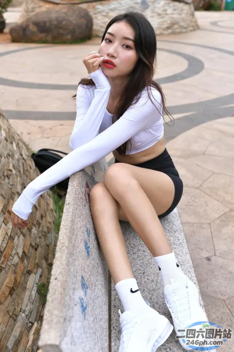 双腿交叉坐在墙上的 Araffed 女人