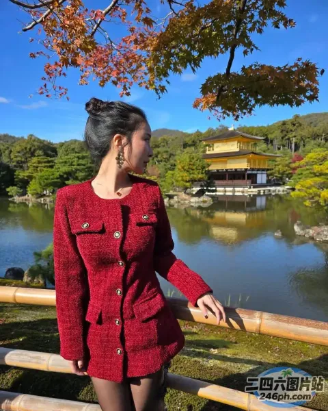 身穿红色夹克的阿拉夫德女子站在池塘边的栅栏旁
