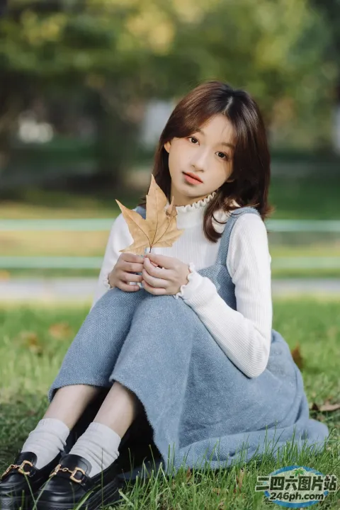 一个女人坐在地上，手里拿着一片叶子
