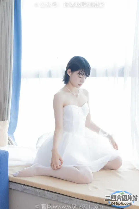 坐在床上、穿着白色连衣裙的 arafed 女人