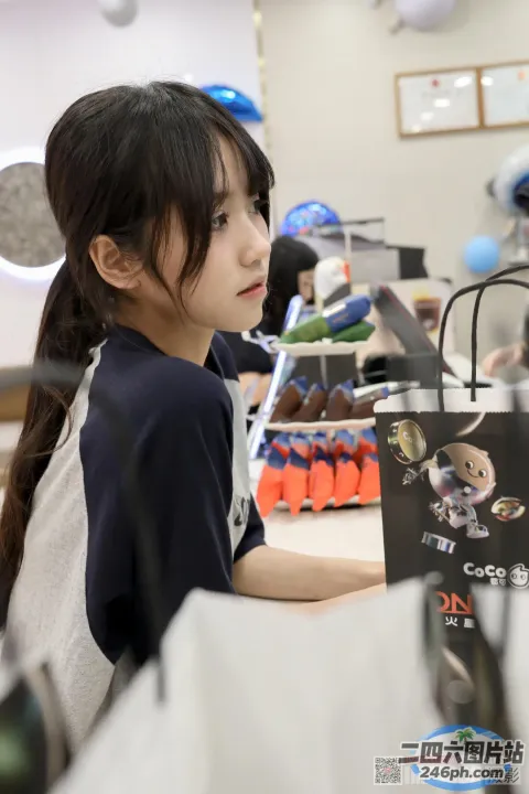 桌旁坐着一个年轻女孩，手里拿着一本书
