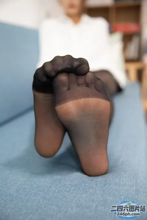 有一个女人坐在沙发上，双脚抬起