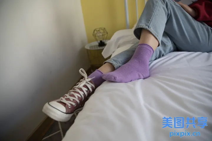 有人躺在床上，双脚抬起，穿着紫色袜子