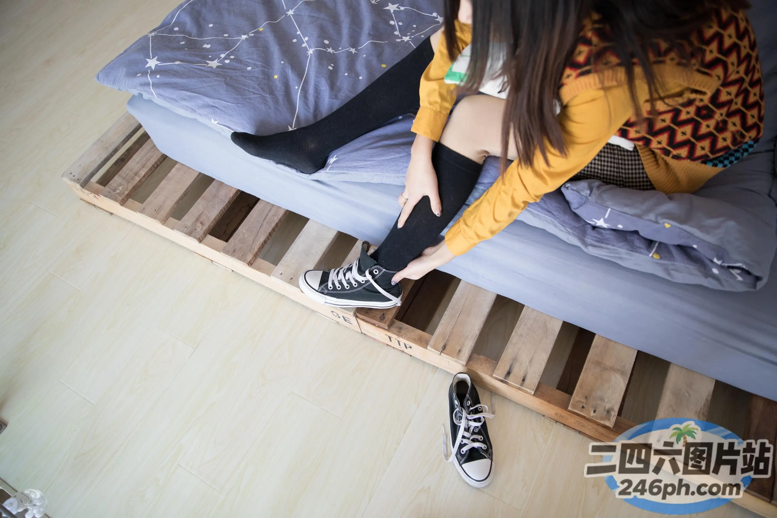 阿拉菲坐在床上，穿着一双黑色鞋子