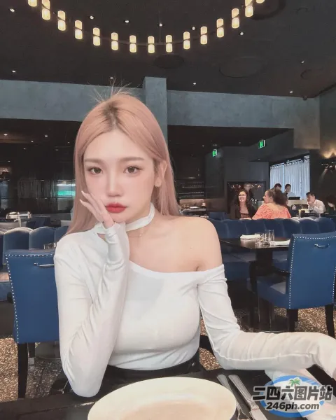 一个女人坐在桌子旁，手里拿着一盘食物