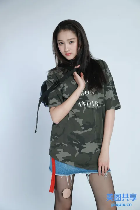 身穿迷彩衫和蓝色裙子的 araffe 女子合影留念