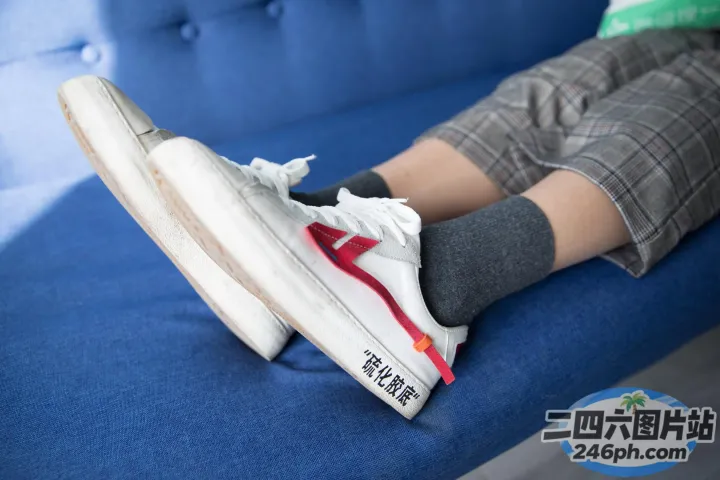 有人坐在蓝色沙发上，双脚抬起
