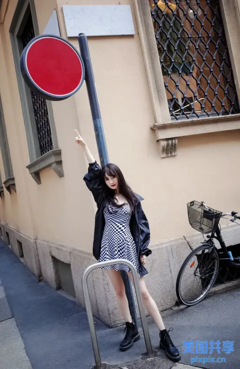 有一女子站在杆子上的红色牌子旁边