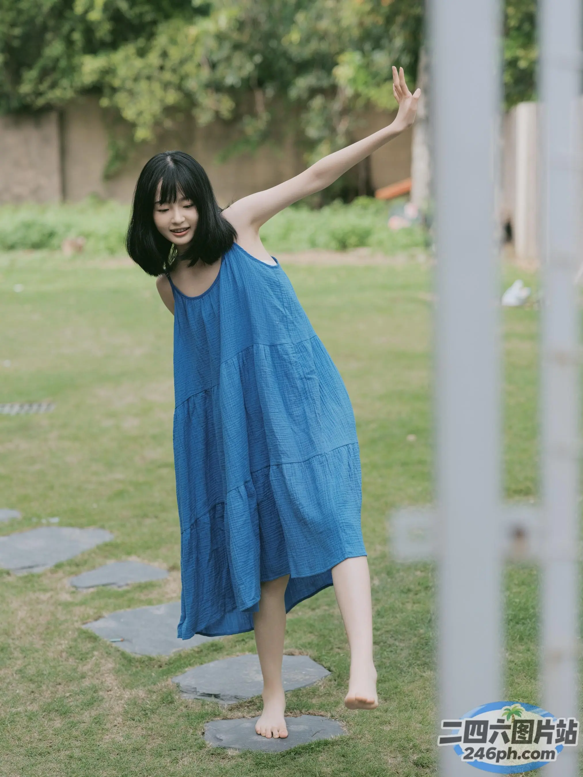 站在公园踏脚石上的蓝色连衣裙的 araffe 女子
