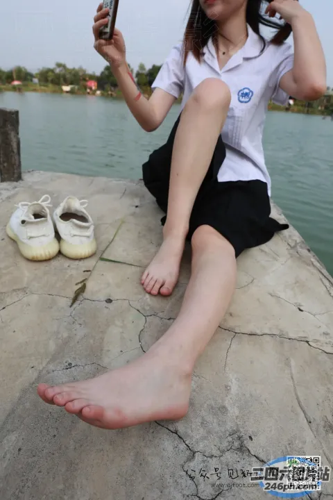 有个女人拿着手机坐在石头上