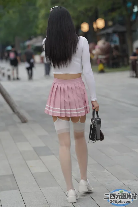 穿着裙子和紧身丝袜的 Araffed 亚洲女子走在人行道上