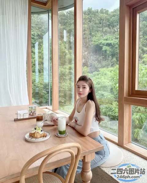 有个女人坐在桌子旁，手里拿着一杯咖啡