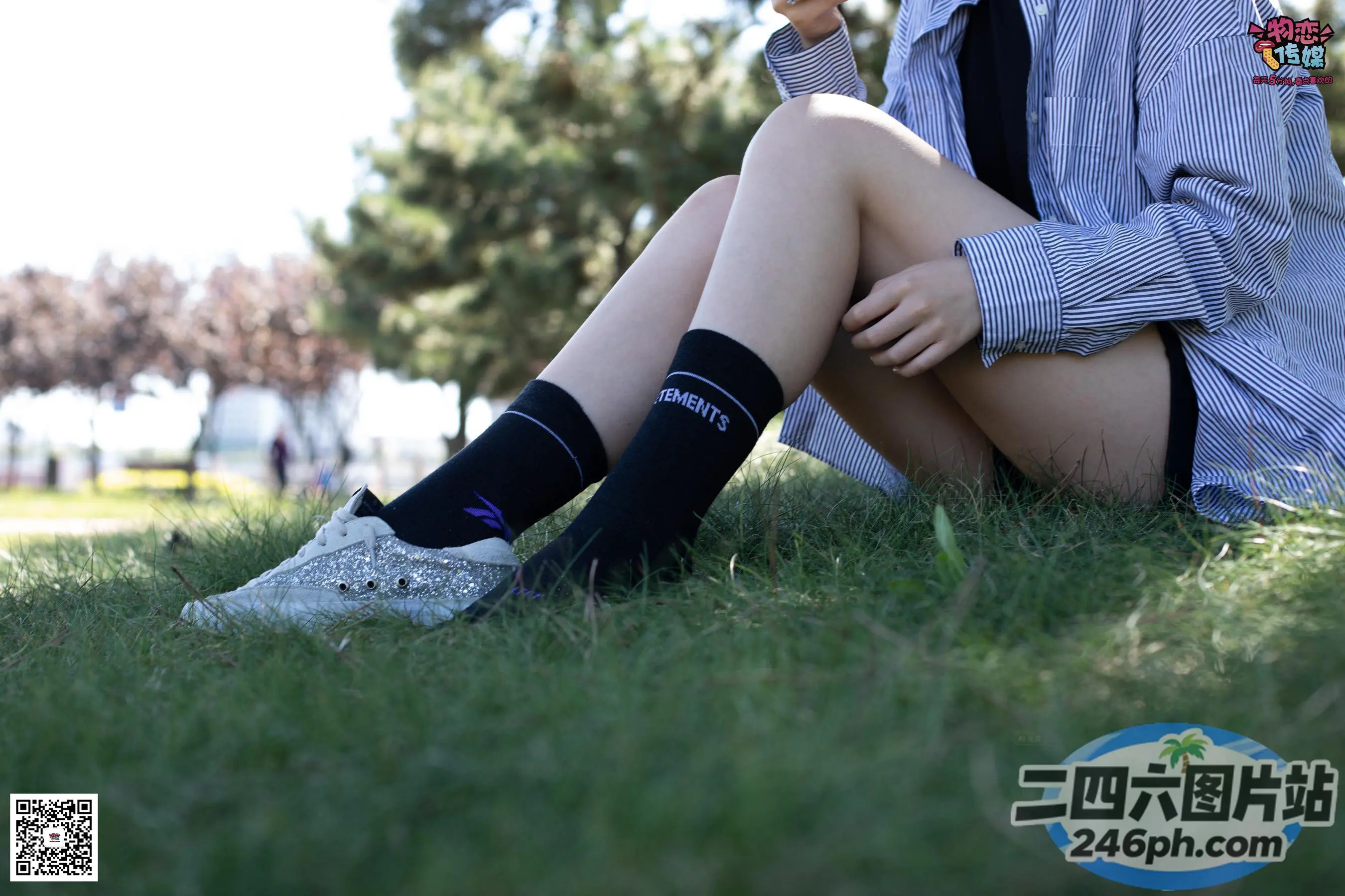 阿拉菲坐在草地上，双腿交叉，衬衫塞进去