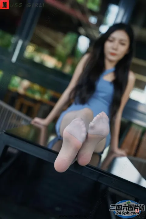 穿着蓝色连衣裙的 Araffed 女人坐在桌子上，双脚抬起