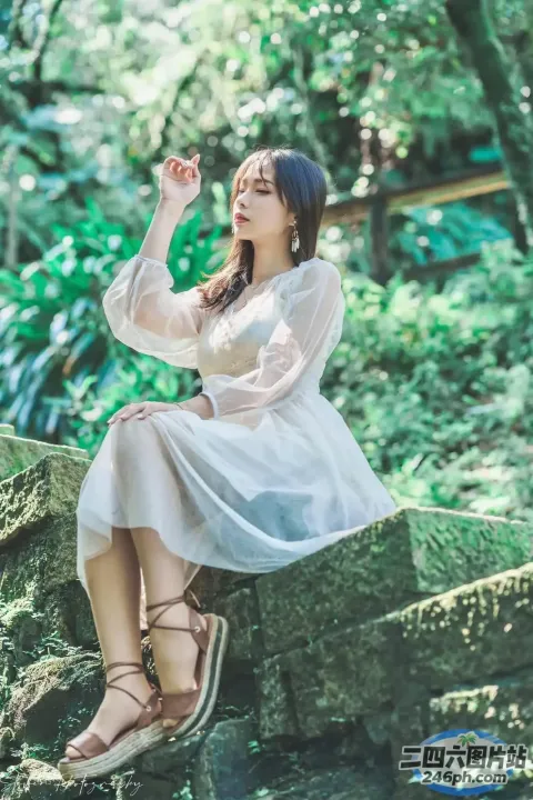 一个穿着白色连衣裙坐在石架上的女人