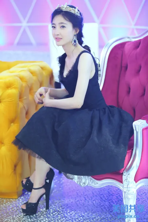 身穿黑色连衣裙的阿拉夫女人坐在粉红色的椅子上