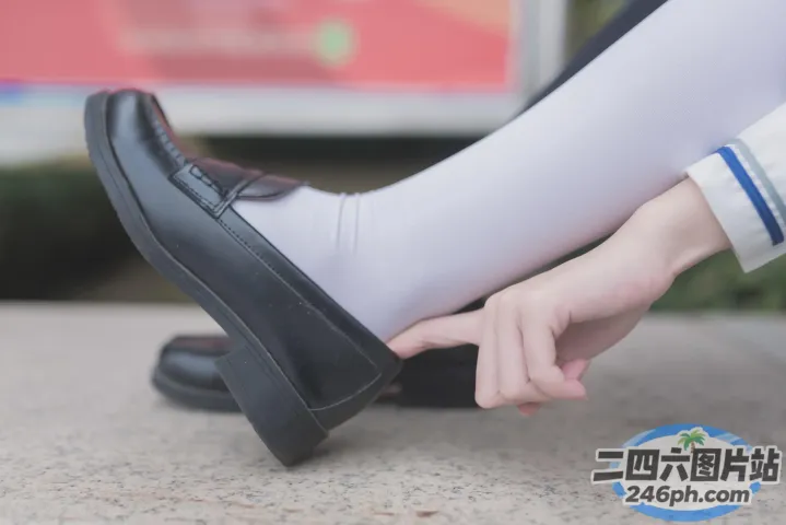 有人穿着白色袜子和黑色鞋子，手里拿着一只黑色的鞋子
